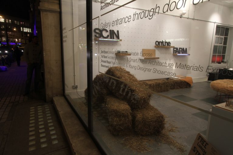 View through gallery window osf straw bales and strawboard shelves on wall